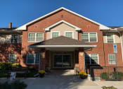 Thumbnail 3 of 17 - A red brick building with a covered entrance and a small porch.