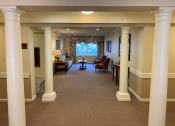 Thumbnail 13 of 17 - A hallway with white columns and a carpeted floor.