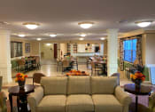 Thumbnail 11 of 17 - Community room with a couch, chairs, and large dining tables.