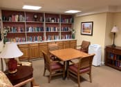 Thumbnail 12 of 17 - A library with a table, chairs, and bookshelves.