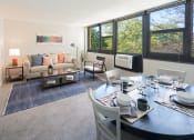 Thumbnail 5 of 39 - Living room layout with couch, dining set, and large windows at Eden Commons, Chicago