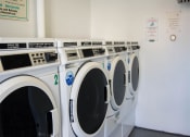 Thumbnail 12 of 18 - Row of washing machines in a laundry room at Brookwood at Bay Shore in Bay Shore, NY 11706