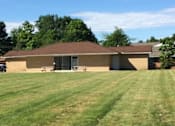 Thumbnail 19 of 33 - a brick building where the party center is located with a large grass lawn in front of it
