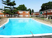 Thumbnail 27 of 27 - a large blue swimming pool in front of a brick apartment building
