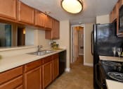 Thumbnail 4 of 13 - Kitchen with black appliances and wooden cabinets at Broadwater Apartments in St Petersburg, FL 33711