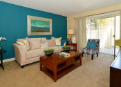Thumbnail 1 of 13 - Living room with blue walls and a tan couch at Broadwater Apartments in St Petersburg, FL 33711