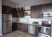 Thumbnail 6 of 37 - A kitchen with dark wood cabinets and stainless steel appliances  at RoCo Apartments, Fargo, North Dakota 58102