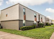 Thumbnail 7 of 17 - Apartment building exterior with manicured lawn and mature trees