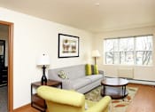 Thumbnail 10 of 12 - A living room with a grey couch, yellow chair, and a lamp on a side table.