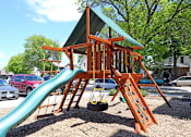 Thumbnail 12 of 12 - A playground with a green slide and a red car parked in the background.