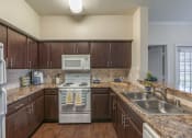 Thumbnail 14 of 44 - Two Bedroom Apartments in Spring TX - Edgewater at Klein - Spacious Kitchen with Wood-Style Cabinets and Marble Style Countertops