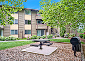 Thumbnail 6 of 19 - Exterior view of patio area and BBQ, manicured grounds and building, and blue skies in the background at Heritage Grove, Renton, WA.