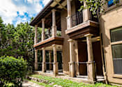 Thumbnail 34 of 48 - Multi story building with stone columns and covered balconies at Nalle Woods of Westlake Apartments, Austin, TX