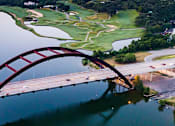 Thumbnail 48 of 48 - Aerial view of arched bridge over lake at Nalle Woods of Westlake Apartments, Austin, 78746
