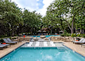 Thumbnail 12 of 48 - Swimming pool with built in spa and lounge seating at Nalle Woods of Westlake Apartments, Austin, TX 78746