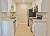 Thumbnail 7 of 33 - Kitchen view with stainless appliances, white cabinets, stone counters, and wood look flooring.