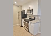 Thumbnail 6 of 33 - Kitchen view with stainless appliances, white cabinets, stone counters and wood look flooring