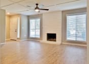 Thumbnail 4 of 33 - View of living area with wood look flooring, two well lit window, ceiling fan, and wood burning fireplace