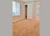 Thumbnail 10 of 33 - Bedroom view with carpet flooring, well lit window, and closet door open showing built in shelfing
