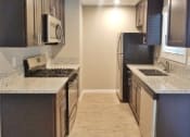 Thumbnail 1 of 33 - View of kitchen with stone counters, stainless appliances, brown cabinets, and wood look flooring