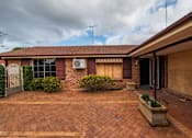 Thumbnail 6 of 12 - A house with a red brick driveway and a white air conditioning unit on the wall.