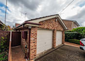 Thumbnail 4 of 12 - A house with a white garage door and a brown brick wall.