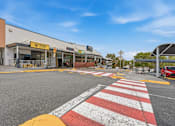 Thumbnail 2 of 20 - A red and white zebra crossing in front of a building with a yellow sign that says "KFC".