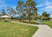 Thumbnail 11 of 20 - A park with a walking path, a gazebo, and a playground.
