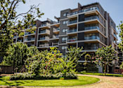 Thumbnail 8 of 17 - A modern apartment building with a well-maintained lawn in front.
