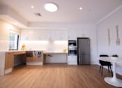 Thumbnail 5 of 9 - A kitchen with a refrigerator, a table, and a counter.