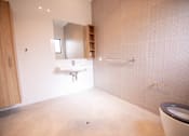 Thumbnail 7 of 9 - A bathroom with a toilet, sink, and mirror.