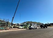 Thumbnail 5 of 9 - A construction site with a white car and a black truck parked in front of a building under construction.