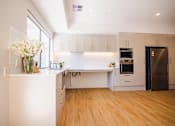 Thumbnail 9 of 12 - A kitchen with white cabinets and a wooden floor.