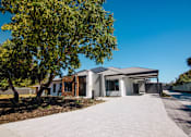 Thumbnail 2 of 12 - A house with a grey roof and a tree in front of it.
