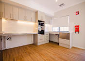 Thumbnail 11 of 12 - A kitchen with wooden floors and white cabinets.