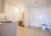 Thumbnail 6 of 12 - A white bathroom with a sink, toilet, and shower.