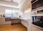 Thumbnail 3 of 12 - A modern kitchen with white cabinets and a digital clock on the microwave.