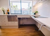 Thumbnail 4 of 12 - A kitchen with a white counter and wooden floors.
