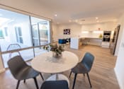 Thumbnail 6 of 11 - A dining area with a white table and chairs.