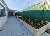 Thumbnail 3 of 11 - A patio with a planter box and a green fence.