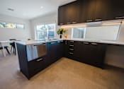 Thumbnail 5 of 9 - A kitchen with black cabinets and a white counter.
