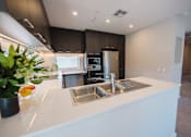 Thumbnail 2 of 9 - A modern kitchen with a white countertop and stainless steel appliances.