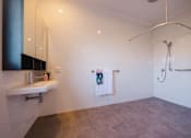 Thumbnail 7 of 9 - A bathroom with a white sink and a shower.