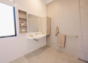 Thumbnail 7 of 15 - A bathroom with a sink and a towel hanging on the shower rod.