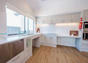 Thumbnail 10 of 15 - A modern kitchen with white appliances and wooden floors.