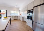 Thumbnail 6 of 15 - A modern kitchen with a stainless steel refrigerator and wooden flooring.