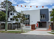 Thumbnail 5 of 6 - A modern building with a white and grey exterior and a red entrance.