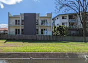 Thumbnail 6 of 6 - A modern house with a grey facade stands in front of a row of houses.