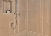 Thumbnail 6 of 6 - A shower area with a wall of tiles and a shower head.