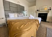 Thumbnail 1 of 12 - a bedroom with a bed and a fireplace